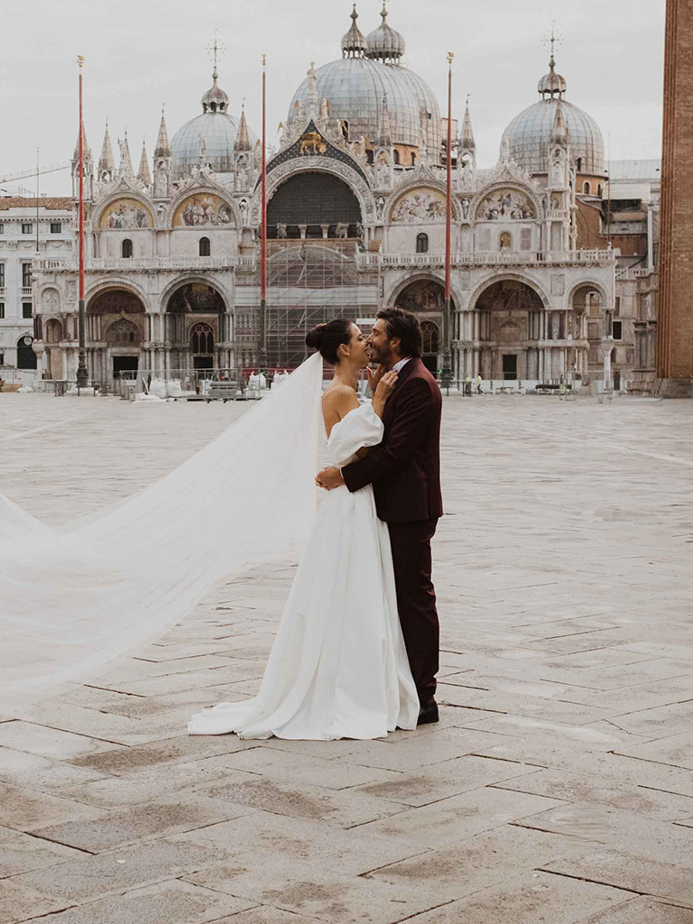 Venice Destination Wedding: a bride and a groom kissing in front of St. Mark's Basilica