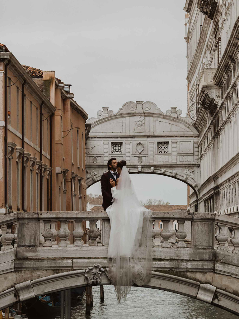 A bride and a groom kissing in front of the Bridge of Sighs in Venice