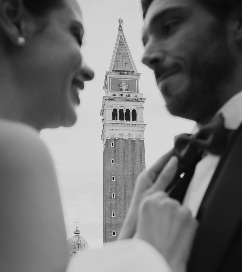 A bride and a groom in front of the St. Mark's Bell Tower in Venice